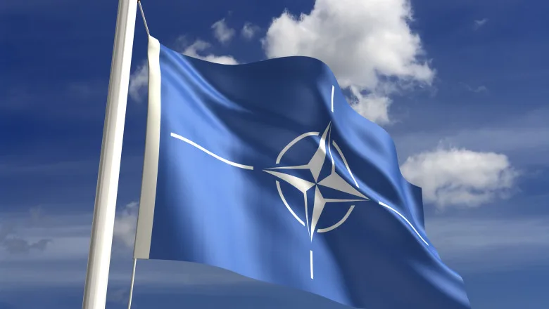 Reuniune NATO cu steaguri ale statelor membre și reprezentanți discutând apărarea colectivă
