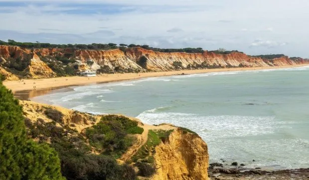 Plajă europeană cu nisip auriu și roșiatic, întinsă pe kilometri